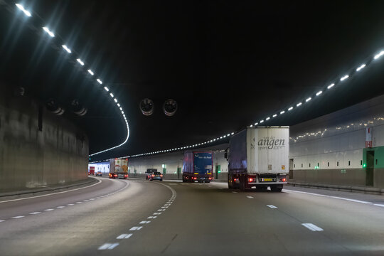 Belgium - November 28 2025: Logistics Trucks Including Van der Sangen and Van de Poel Transport Driving Through Illuminated Highway Tunnel in Antwerp Belgium, Heavy Freight Traffic and Infrastructure