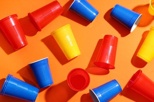 Many colorful plastic cups on orange background