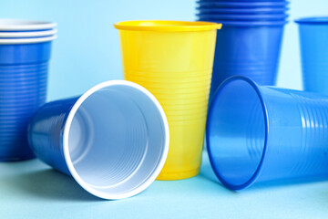 Different plastic cups on blue background, closeup