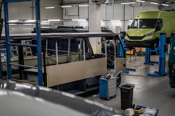 Industrial vehicle manufacturing workshop with metal bus frames and body structures under assembly....