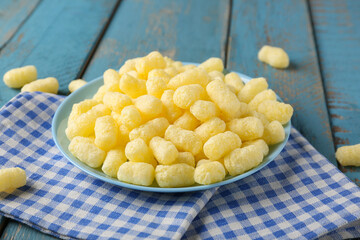 Plate with sweet corn sticks on blue wooden background, closeup
