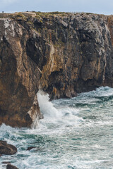 Waves strike the base of rugged cliffs along the Atlantic coast.