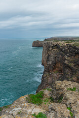 Sheer cliffs plunge into the blue sea along a dramatic and rugged coastline.