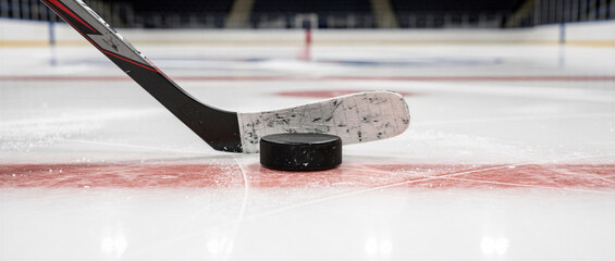 Ice hockey stick and puck positioned on frozen rink during professional arena game preparation
