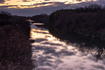 冬の夜明けの入間川と水面に映り込む鮮やかな朝焼けの雲