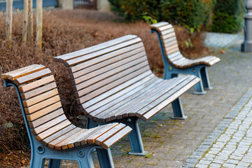 Wooden park benches sitting on sidewalk in public space