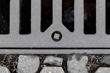 Metal drain grate and paved street surface