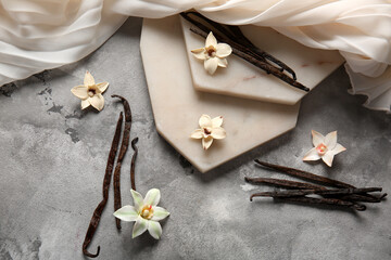 Composition with vanilla sticks, flowers, boards and fabric on grunge background