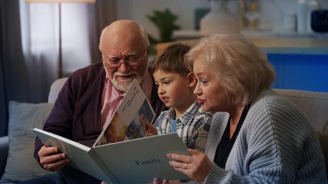 Happy grandparents and grandson looking through family photo album together