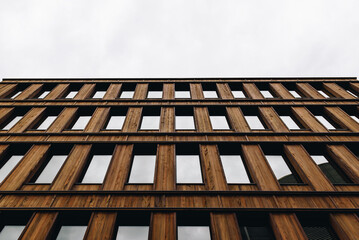 Modern Wooden Office Building Facade With Repeating Windows and Overcast Sky