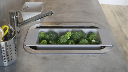 Fresh broccoli placed in a kitchen sink for washing before cooking in a modern kitchen on a sunny day.