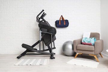 Interior of stylish living room with modern exercising bike, fitball and grey armchair