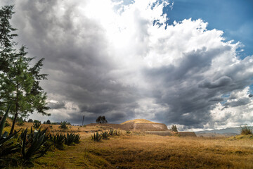 Ancient Tlaloc temple pyramid ruins under dramatic clouds in Calixtlahuaca, Mexico