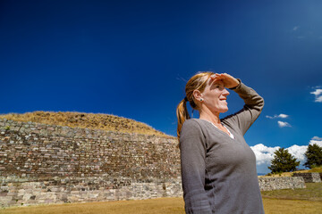 Tourist woman shielding eyes from sun in ancient Tlaloc temple ruins in Calixtlahuaca, Mexico