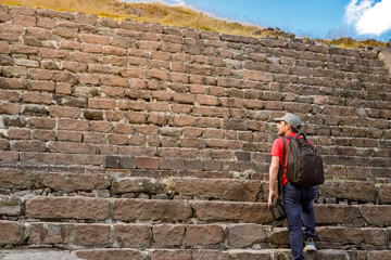 Male tourist climbing the ancient Tlaloc temple steps in Calixtlahuaca, Mexico