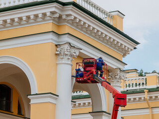 Construction workers on elevated boom on restoration work of historic building
