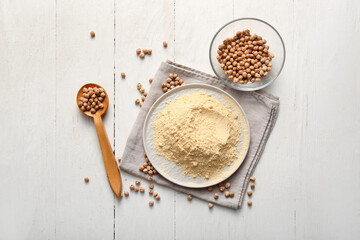 Plate of chickpea flour and glass bowl with beans on white wooden background