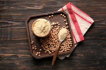 Bowl of chickpea flour and plate with beans on wooden background