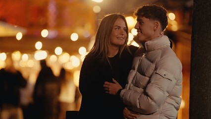 Fototapeta premium A young couple embraces in Paris at night surrounded by bokeh lights The image captures a romantic moment between a man and woman in love during a city break suitable for travel and lifestyle content.
