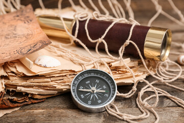 Composition with modern compass, old book and spyglass on wooden background, closeup