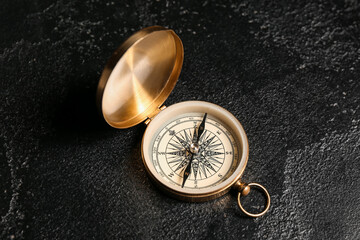 Golden compass on black grunge background, closeup