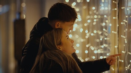 Obraz premium A romantic couple is admiring a Christmas lights display in Paris France at night The young lovers are enjoying the festive season together showcasing love and romance.