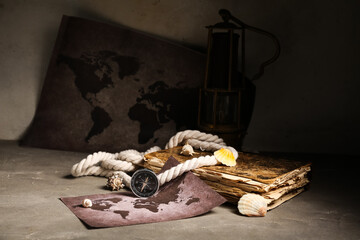 Composition with modern compass, world map, old book, rope and seashells on grey grunge background