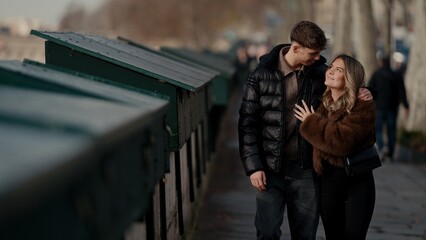A romantic young couple embraces on the bank of the Seine River in Paris France The image conveys...