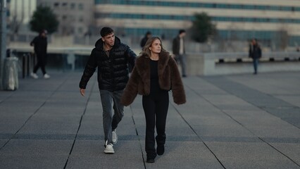 A stylish couple walks together in Paris France wearing fashionable winter clothing The urban city street scene is perfect for travel and romance concepts.