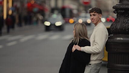 A romantic couple is embracing by a streetlight in Paris France with cars and pedestrians in the...