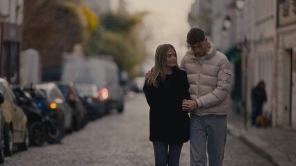 A young couple walks hand-in-hand down a cobblestone street in Paris France enjoying a romantic moment together The image captures the essence of love connection and travel in a beautiful European set
