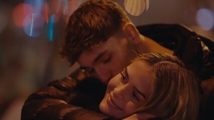 A romantic young couple embraces in Paris France at night with bokeh lights creating a warm and intimate atmosphere. This image is perfect for illustrating love travel and relationships.