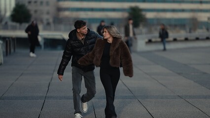 A young couple walks together in Paris France enjoying a romantic moment outdoors The man and woman are dressed in stylish casual clothing as they explore the urban cityscape showcasing a travel lifes