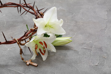 Crown of thorns, white lilies and prayer beads on grey background
