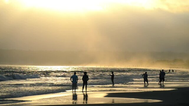 Silhouettes and shadows of people along the beach at dusk
