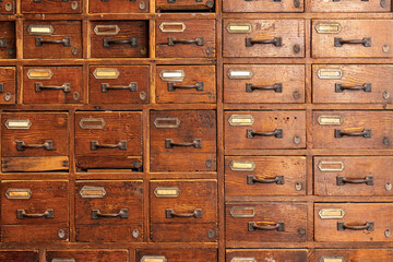 Close-up of an old wooden drawer cabinet with metal handles, showing rustic texture, warm tones, and vintage storage organization concept.