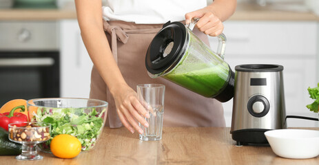 Young woman making healthy smoothie in kitchen