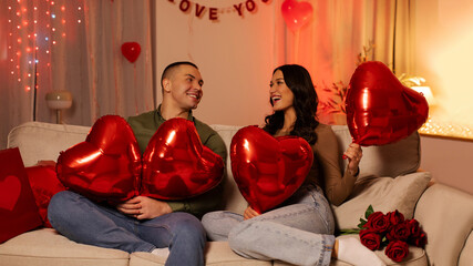 Loving European man and woman celebrating Valentine's day in romantic home atmosphere, sitting on...