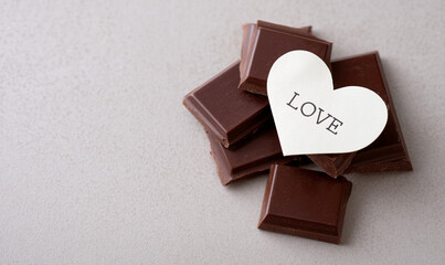 Dark Chocolate Pieces with Heart Shaped Love Card on Light Background Showing Sweet Affection. generative aI