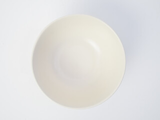 Top view of a clean, empty white ceramic bowl isolated on a white background
