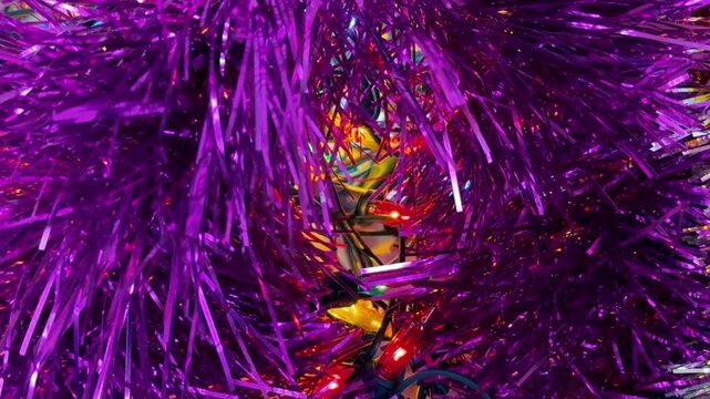 Purple Christmas tinsel and flicker garland lights. Close up of holidays decorations. New Year festive background. Holidays 4k footage.