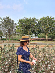 Mature woman in a dress and straw hat on a cotton plantation.