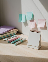 Vertical closeup of blank desk calendar and markers on wooden desk with sticky notes on wall