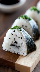 Close-up of onigiri rice ball with seaweed and sesame seeds on wooden board  