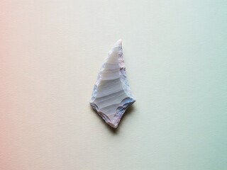 Elegant ancient arrowhead isolated on textured surface, studio shot
