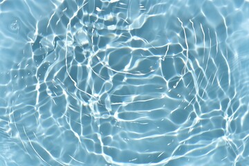 Blue water with ripples on the surface. Defocus blurred transparent blue colored clear calm water surface texture with splashes and bubbles. Water waves with shining pattern texture background.