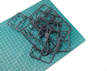 Abstract Backgrounds of Black Plastic Frame for Model Kit. Plastic model kit frame with green cutting mat background with striped pattern. Building Robot Model Kit