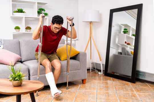 Man recovering from leg injury with crutches at home