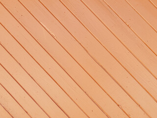 Wooden planks set diagonally show a peach colored painted surface with visible texture and subtle lines the pattern is simple clean and creates a warm geometric effect