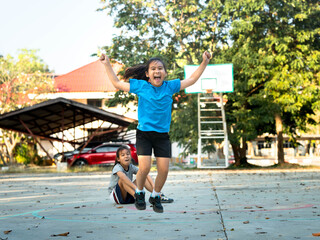 Happy young girl jumping with joy on outdoor basketball court